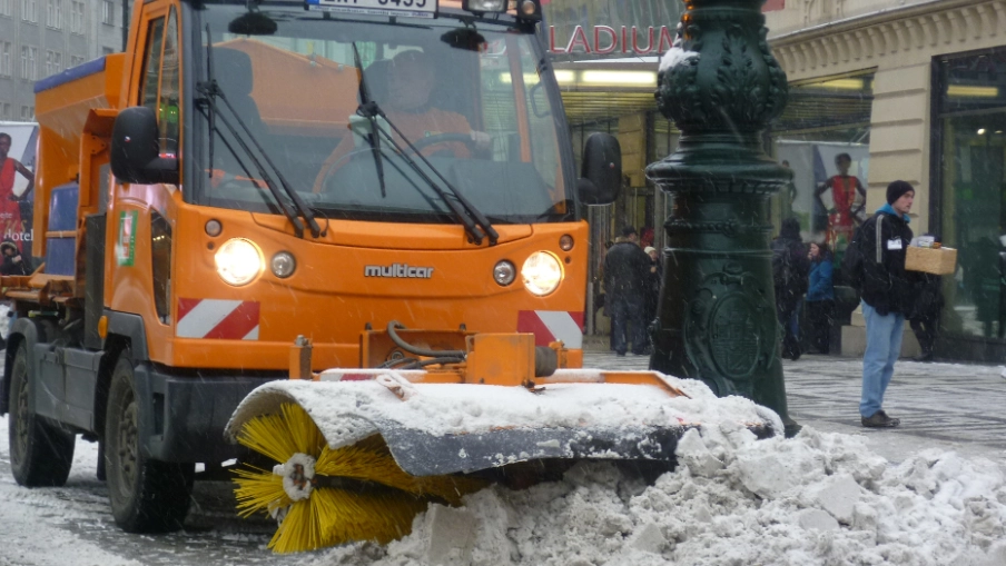 Pohled na auto zimní údržby, odhrabávající sníh z ulice v Praze.
